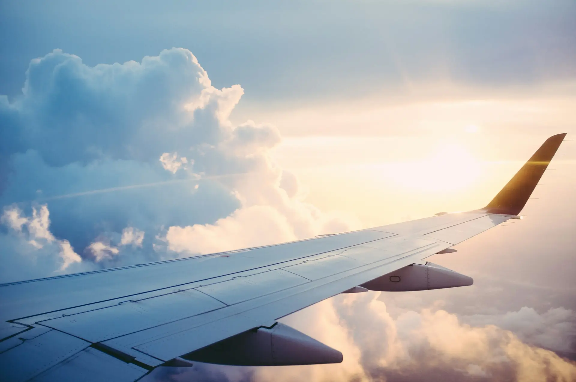 Airplane wing above the clouds at sunset — business travel
